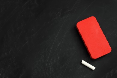 Photo of White chalk and duster on black board, flat lay. Space for text