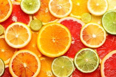 Photo of Slices of fresh citrus fruits as background, top view