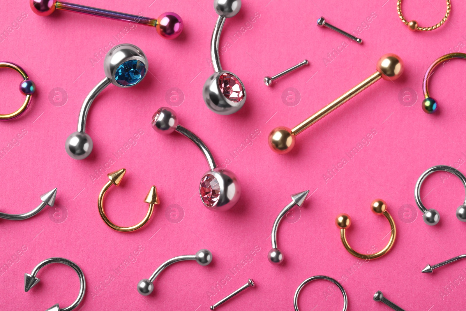 Photo of Stylish piercing jewelry on pink background, flat lay