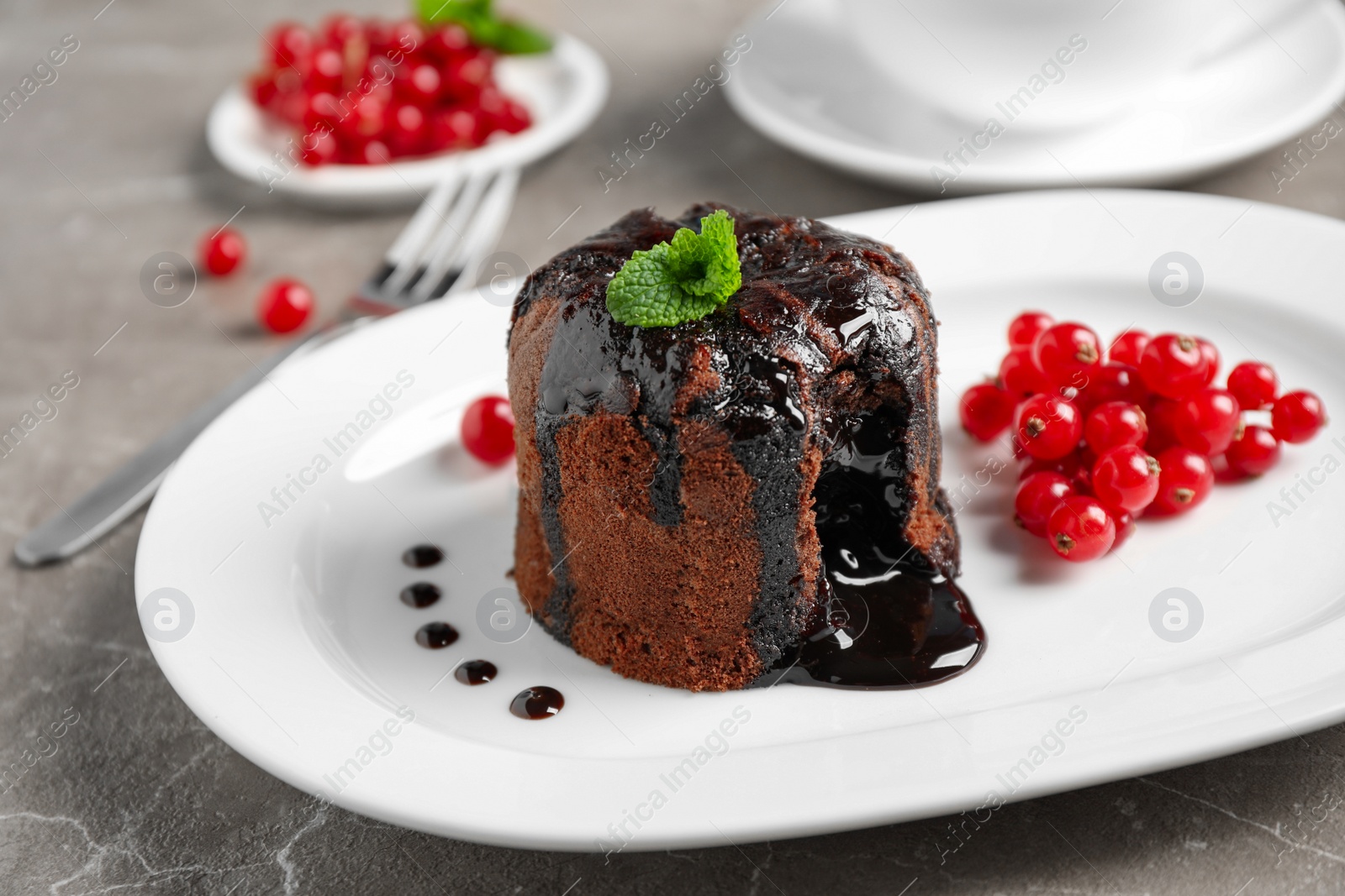 Photo of Delicious warm chocolate lava cake with mint and berries on marble table, closeup