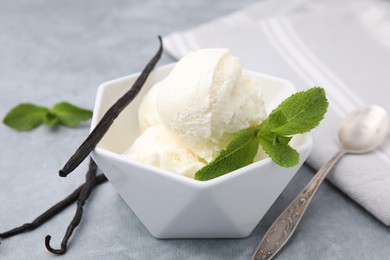 Delicious ice cream, mint, vanilla pods and spoon on light grey table, closeup