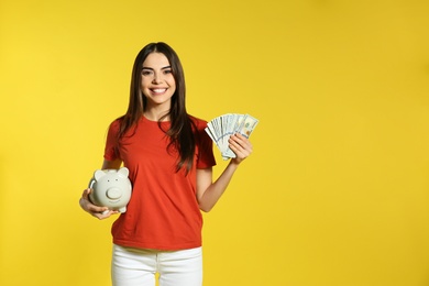Photo of Young woman with piggy bank and money on color background. Space for text