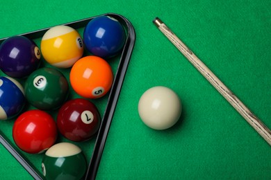 Photo of Set of billiard balls with rack and cue on green table, flat lay