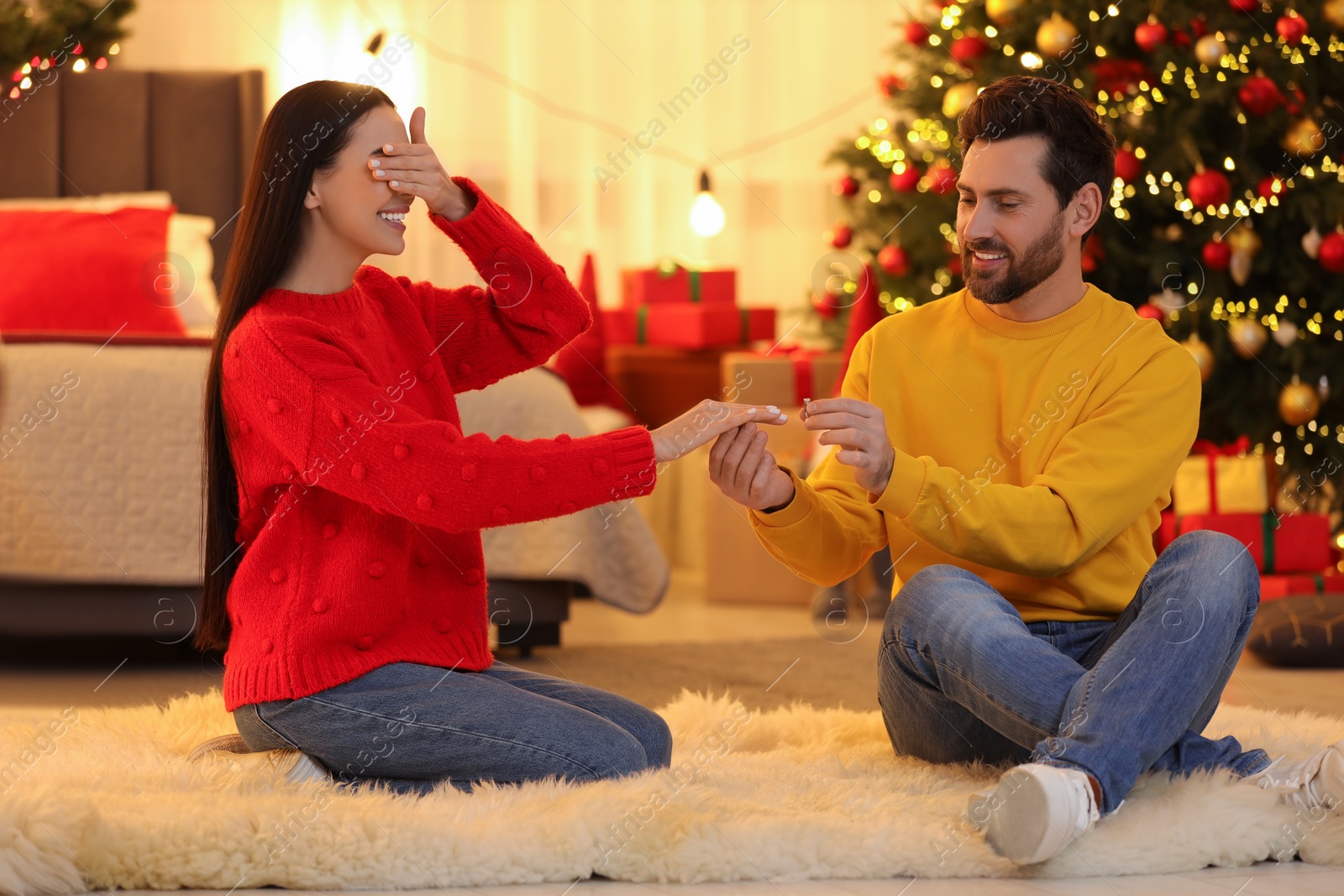 Photo of Making proposal. Man putting engagement ring on his girlfriend's finger at home on Christmas