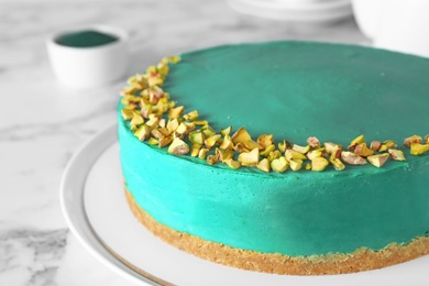 Photo of Delicious homemade spirulina cheesecake decorated with pistachios on marble table