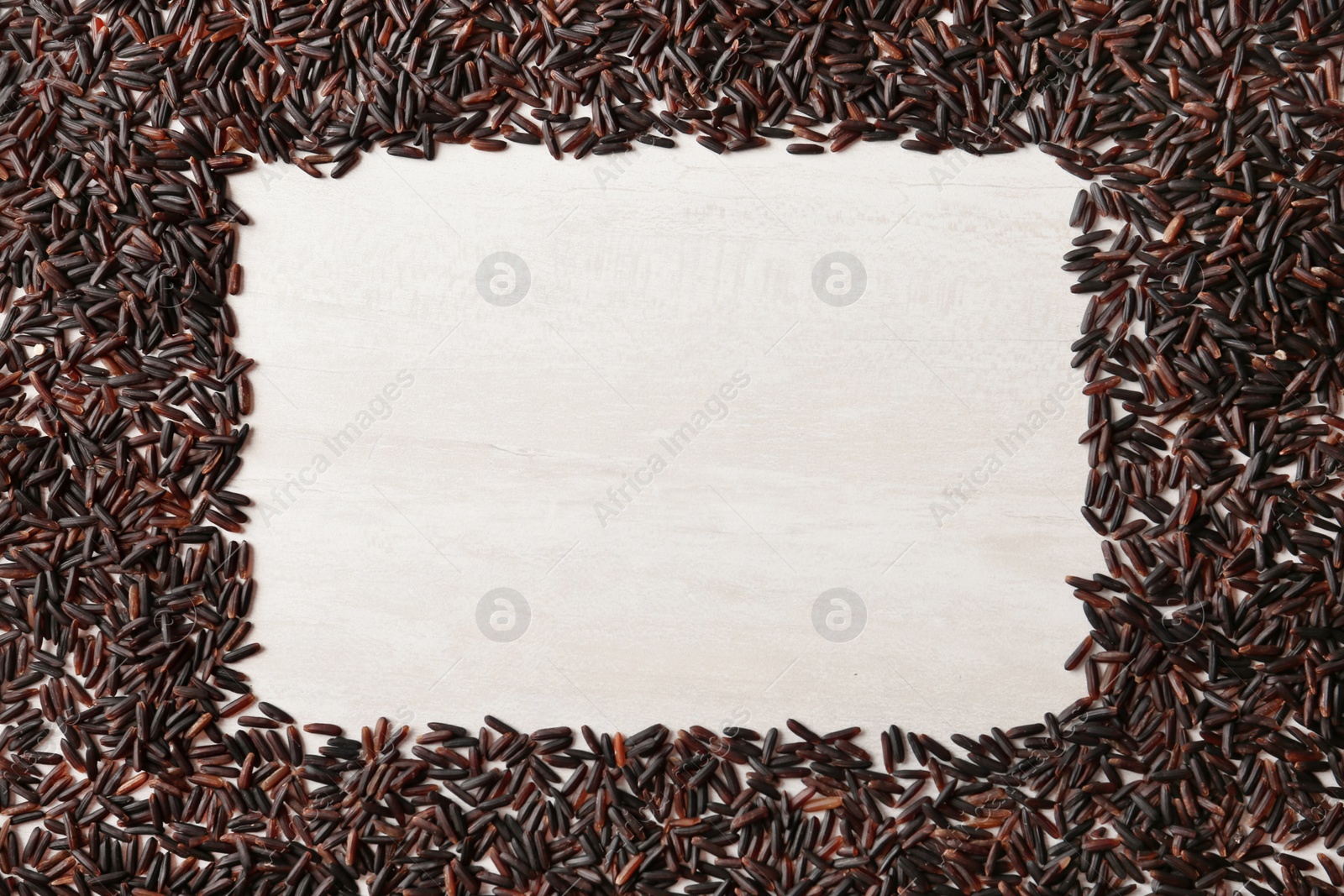 Photo of Frame made with black rice on white wooden background, top view. Space for text