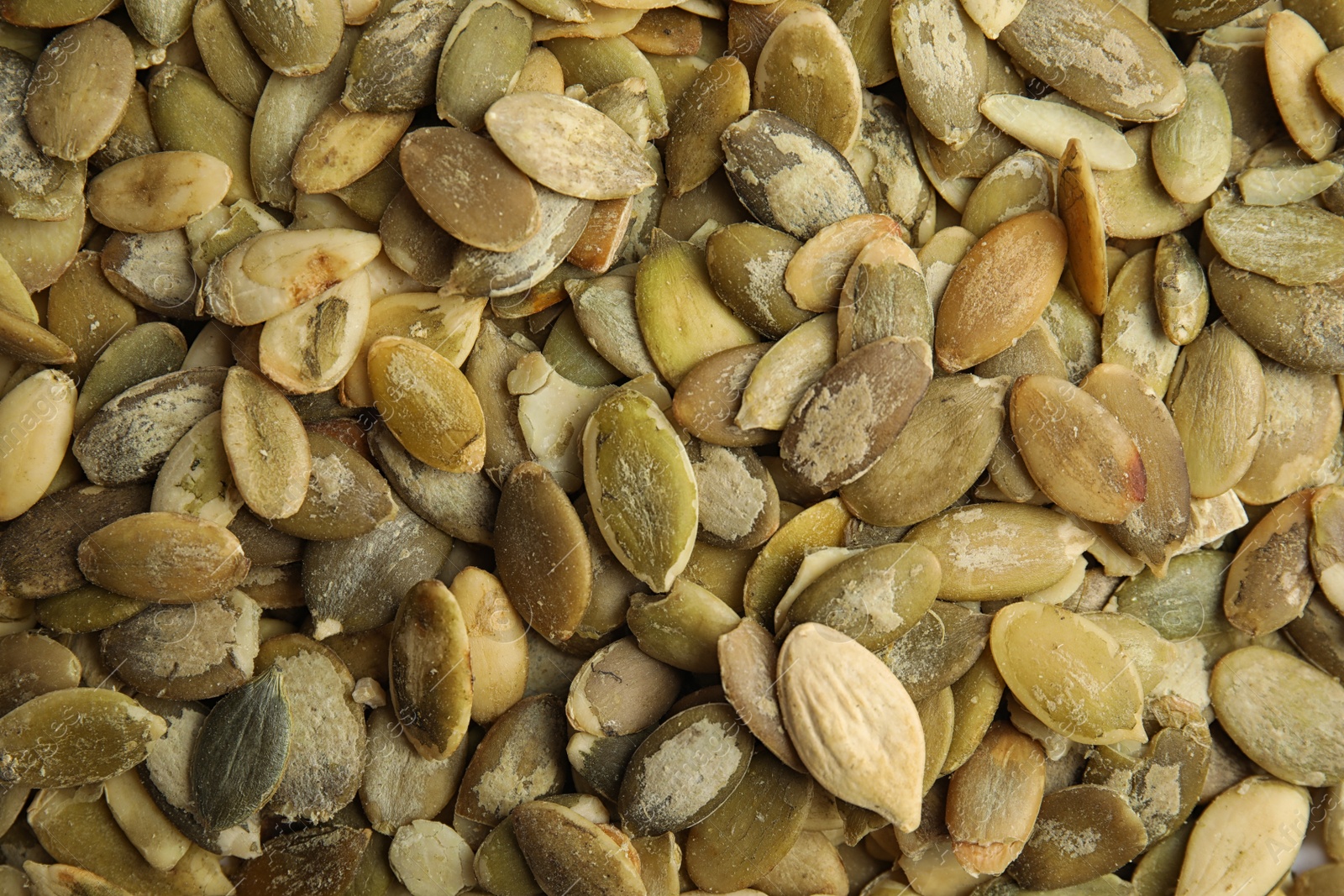 Photo of Raw peeled pumpkin seeds as background, top view