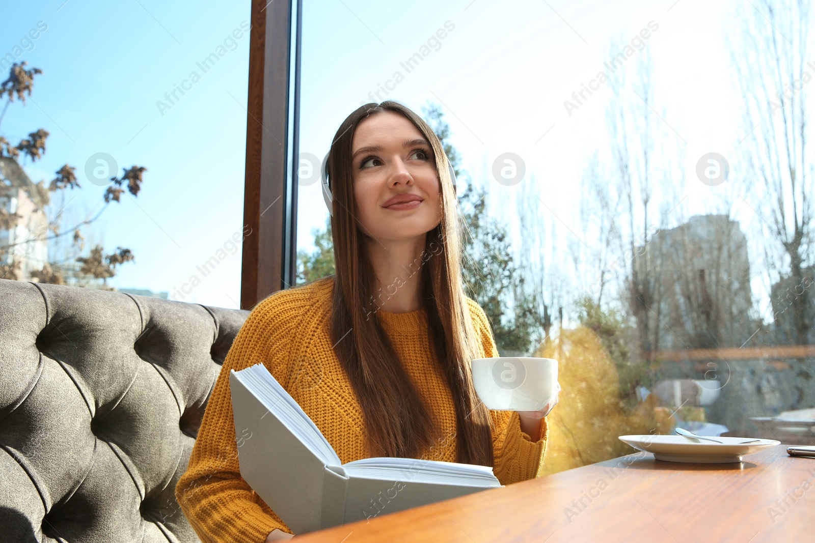 Photo of Woman listening to audiobook at table in cafe