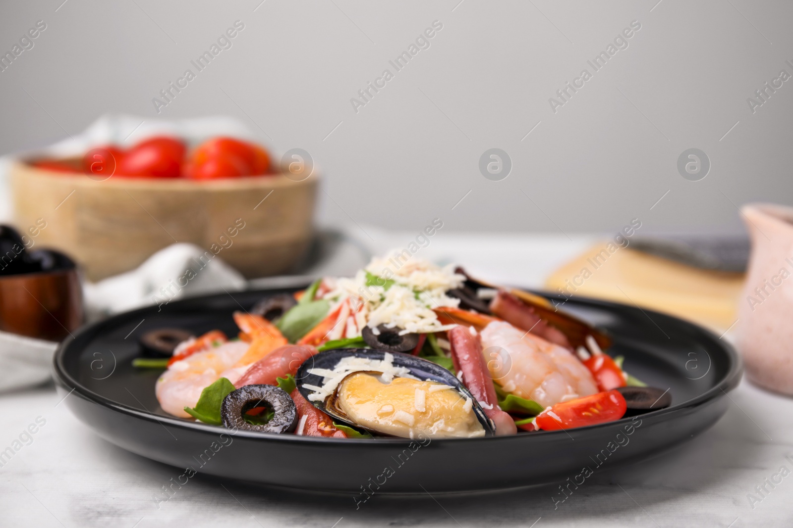 Photo of Plate of delicious salad with seafood on white marble table
