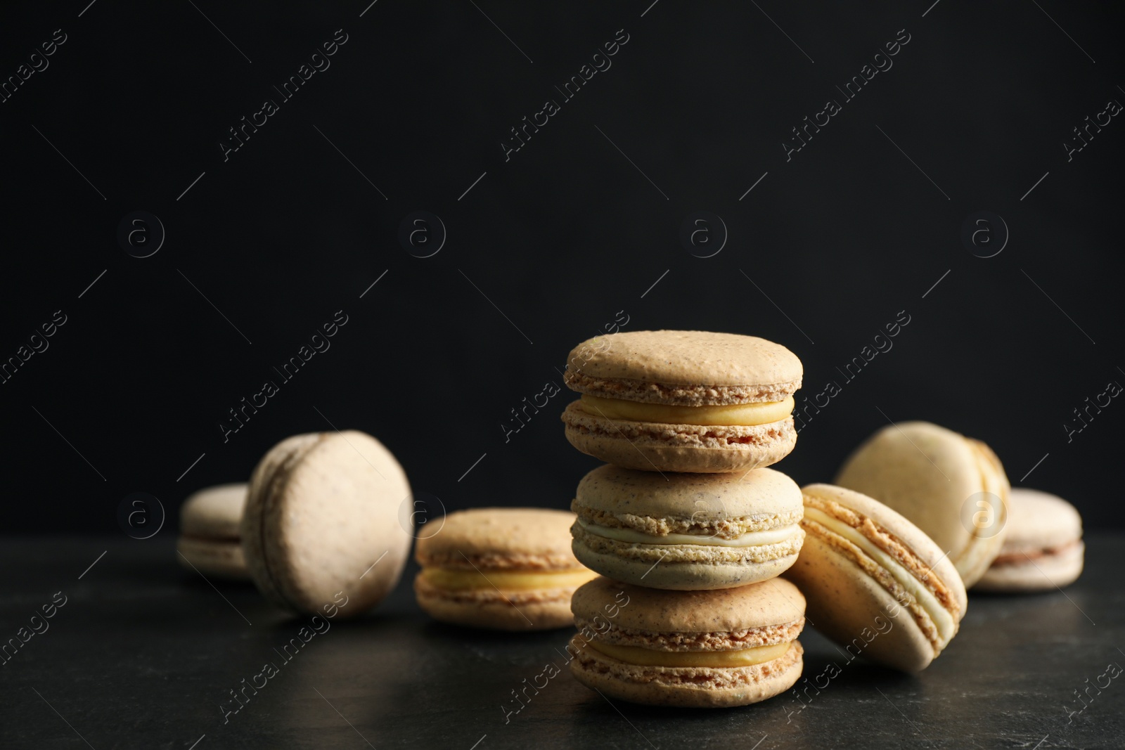 Photo of Delicious macarons on black table. Sweet dessert