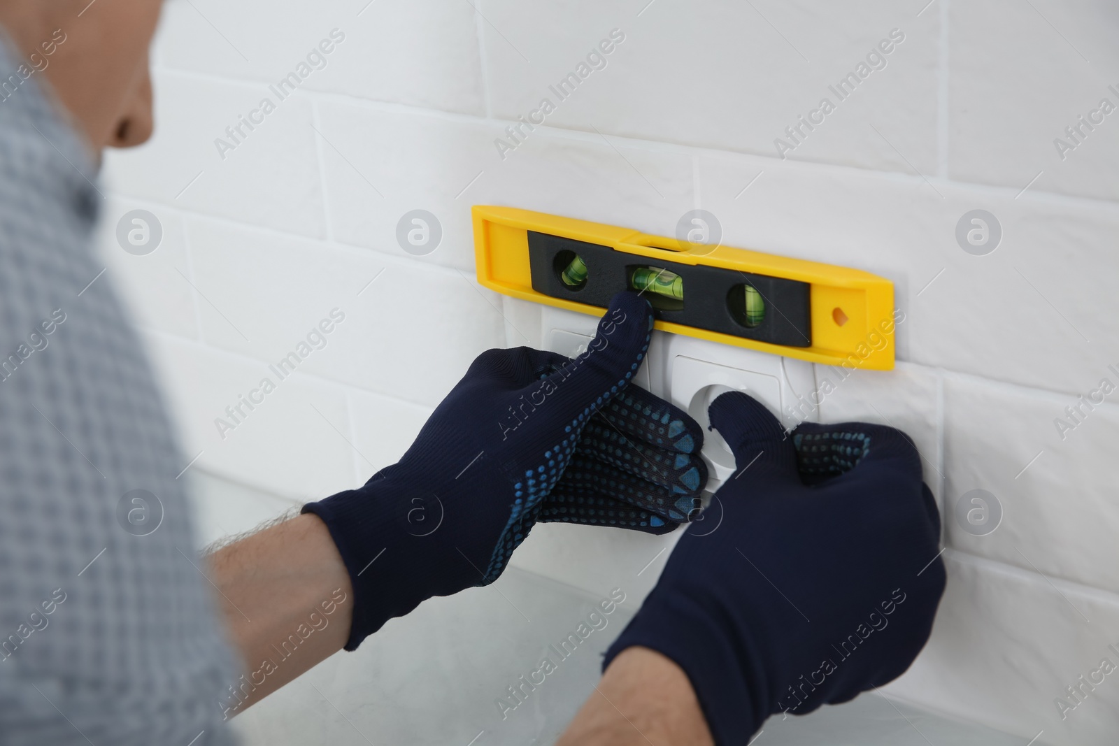 Photo of Professional electrician repairing power socket indoors, closeup