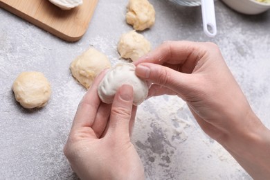 Photo of Woman making dumplings (varenyky) at grey table, closeup