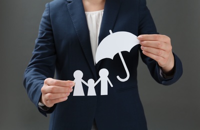 Photo of Woman holding cutout paper family and umbrella, closeup. Life insurance concept