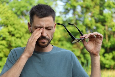 Photo of Man suffering from eyestrain outdoors on sunny day