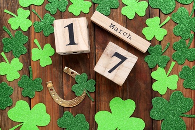 Photo of Flat lay composition with block calendar on wooden table. Saint Patrick's Day celebration