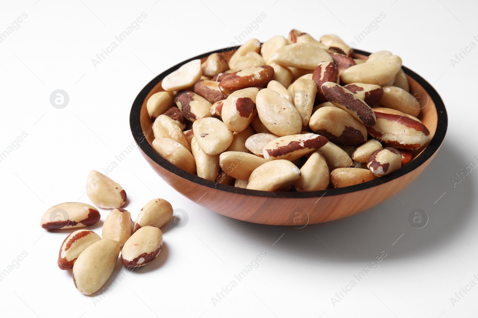 Photo of Wooden bowl with Brazil nuts on white background