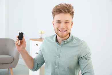 Young man with new car key in dealership