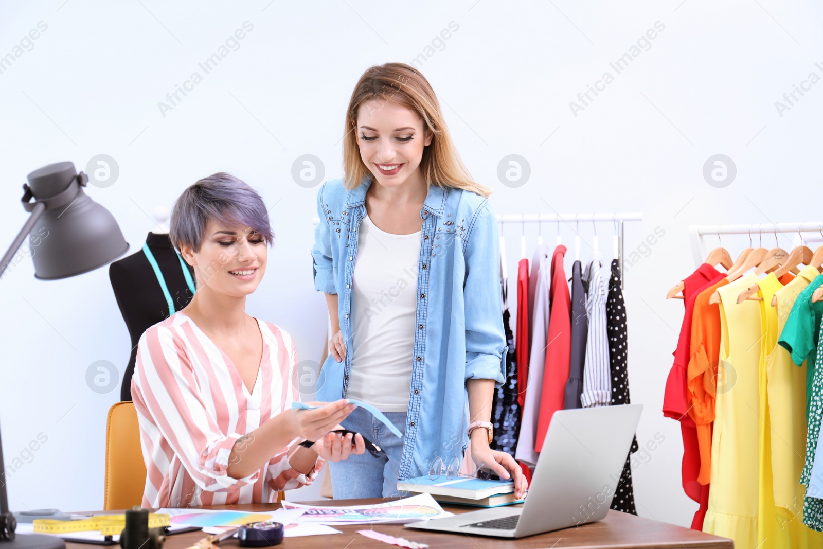 Photo of Young clothes stylist speaking with customer at workplace