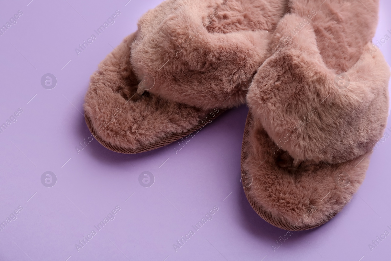 Photo of Pair of stylish soft slippers on violet background