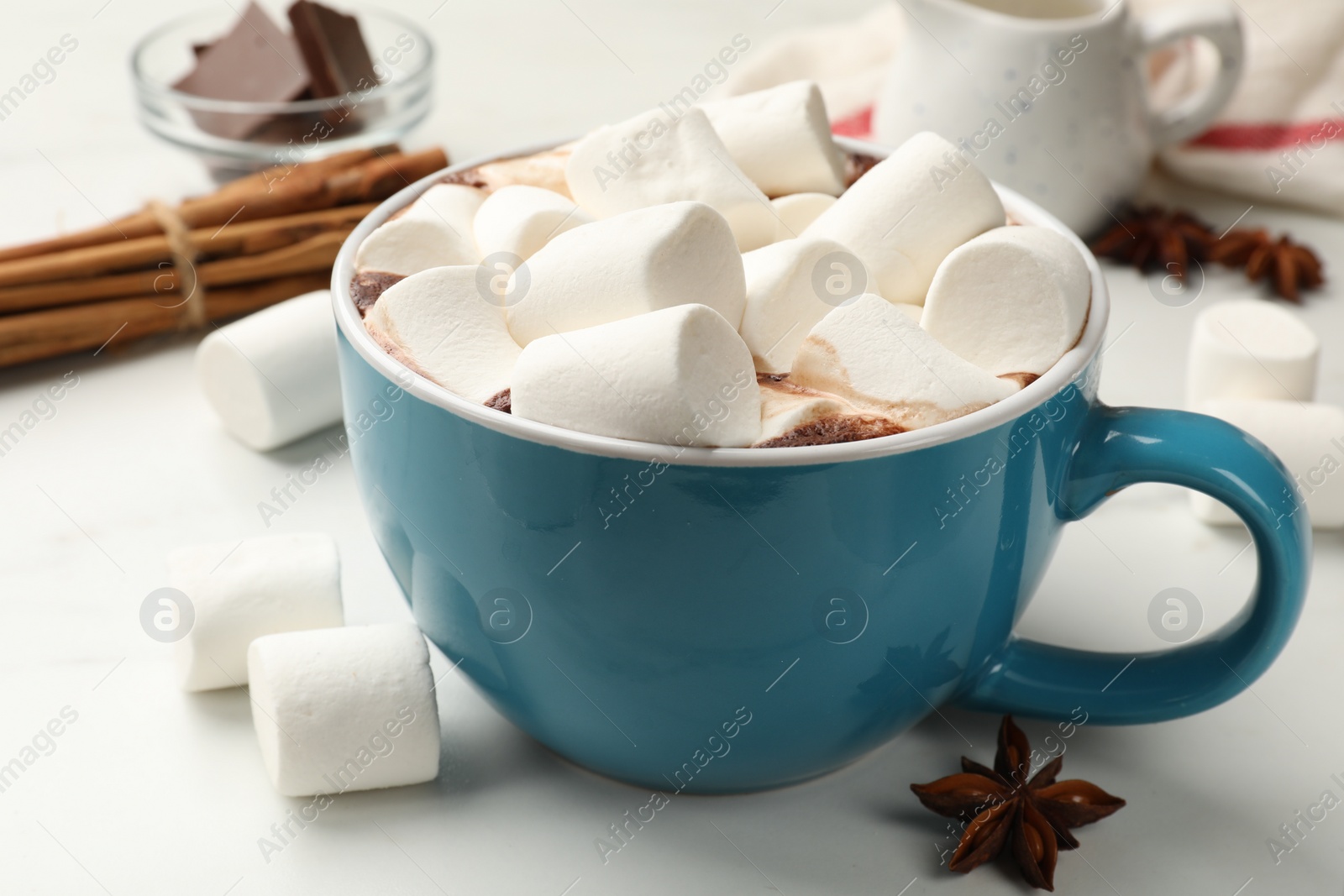 Photo of Tasty hot chocolate with marshmallows and ingredients on white table, closeup