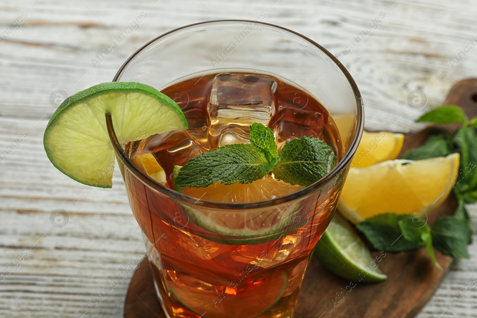 Photo of Glass of delicious iced tea  on white wooden table, closeup