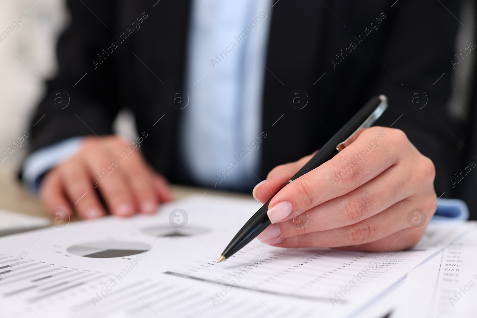 Photo of Secretary doing paperwork at table in office, closeup