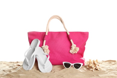 Stylish coral bag and beach accessories on sand against white background