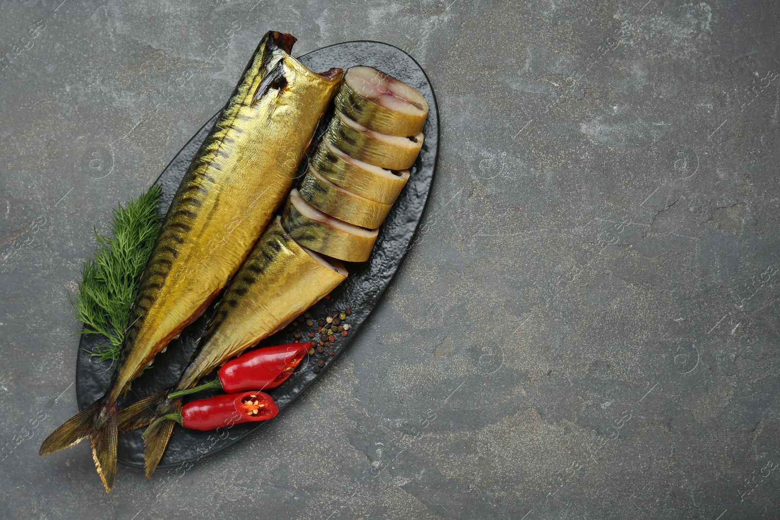 Photo of Delicious smoked mackerels with pepper, dill and spices on dark grey table, top view. Space for text