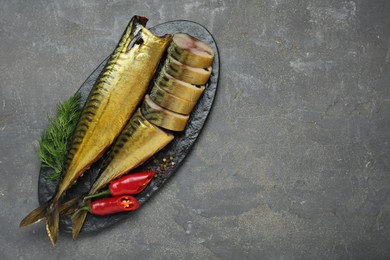 Delicious smoked mackerels with pepper, dill and spices on dark grey table, top view. Space for text