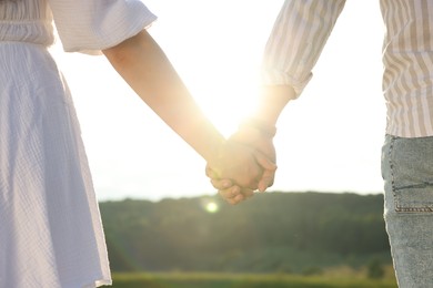 Photo of Romantic date. Couple holding hands outdoors, closeup