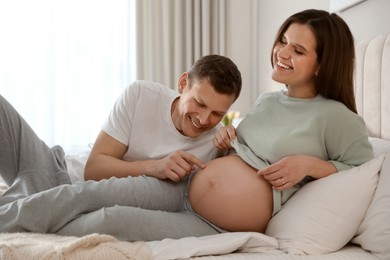 Young pregnant woman with her husband in bedroom