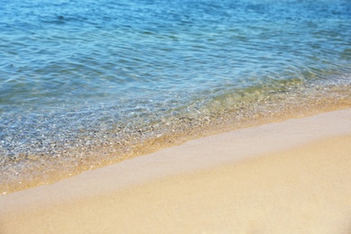 View of sea water and beach sand on sunny day