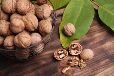 Photo of Walnuts and fresh green leaves on wooden table