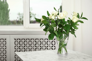 Photo of Glass vase with bouquet of beautiful roses on table in room. Space for text