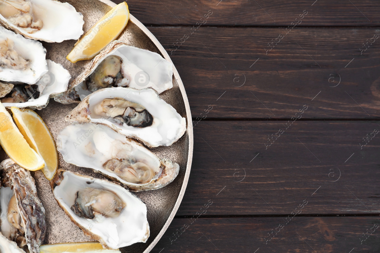 Photo of Fresh oysters with cut juicy lemon and space for text on table, top view