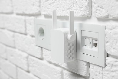 Photo of Wireless Wi-Fi repeater on white brick wall