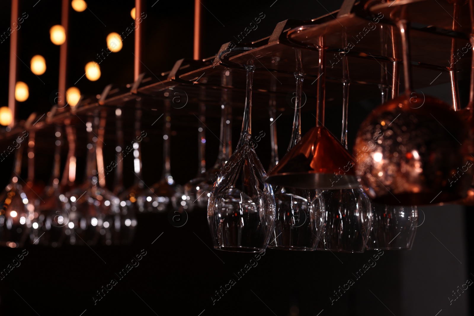 Photo of Different glassware hanging on bar counter, closeup