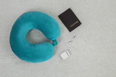 Photo of Soft travel pillow, passport and earphones on grey textured background, flat lay. Space for text