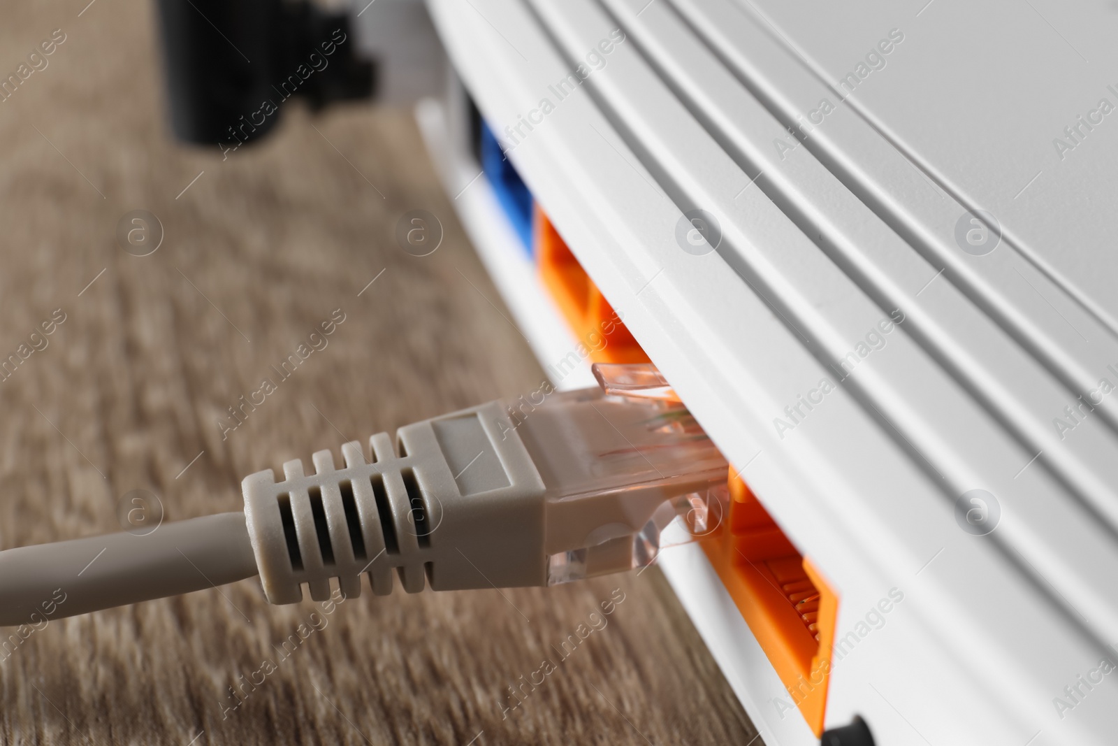 Photo of Connected cable to router on wooden table, closeup. Wireless internet communication