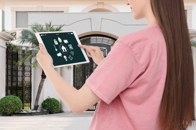 Woman using smart home control system via tablet near house outdoors, closeup
