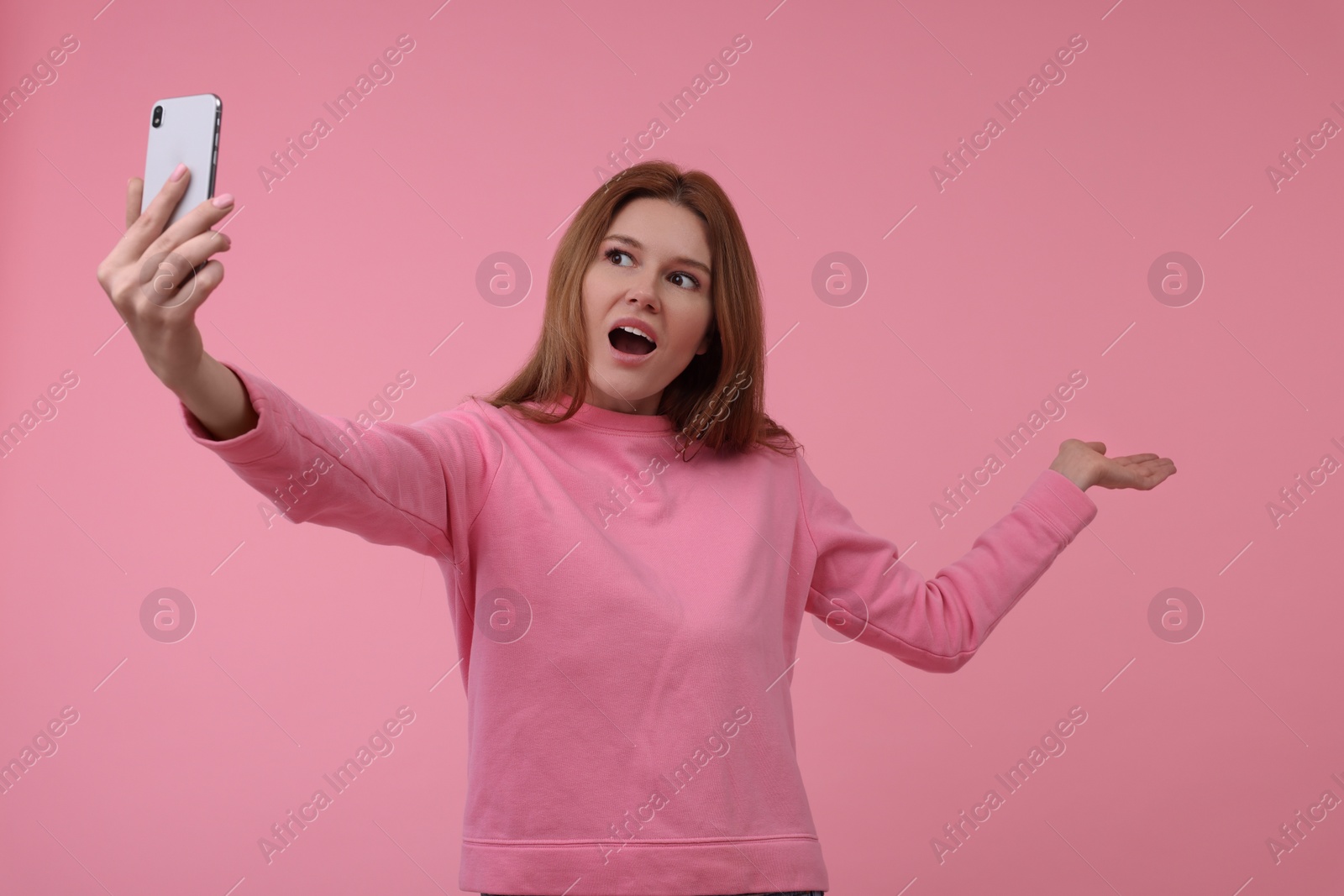 Photo of Beautiful woman taking selfie on pink background