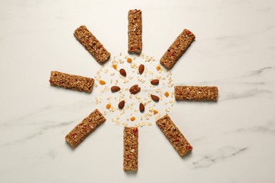 Sun made with tasty granola bars, nuts and oat flakes on white marble table, flat lay