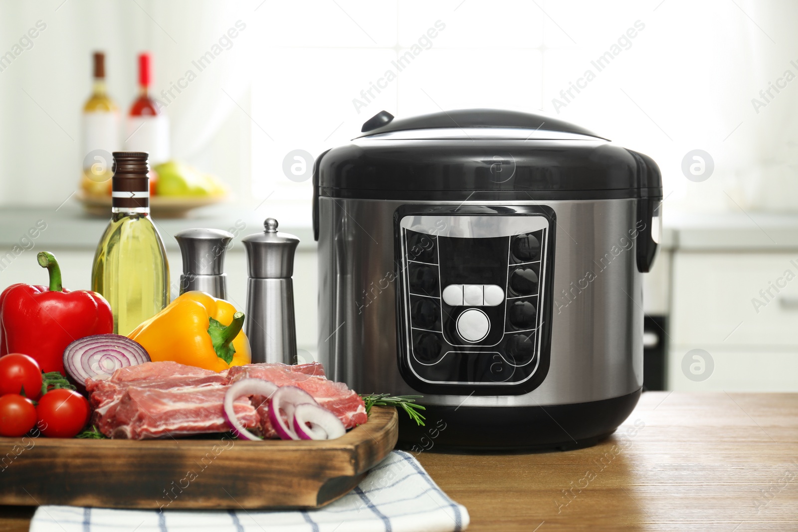 Photo of Modern multi cooker and products on wooden table in kitchen