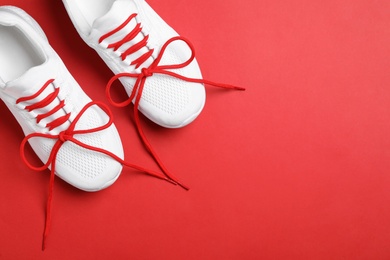Photo of Stylish sneakers with shoe laces on red background, flat lay. Space for text