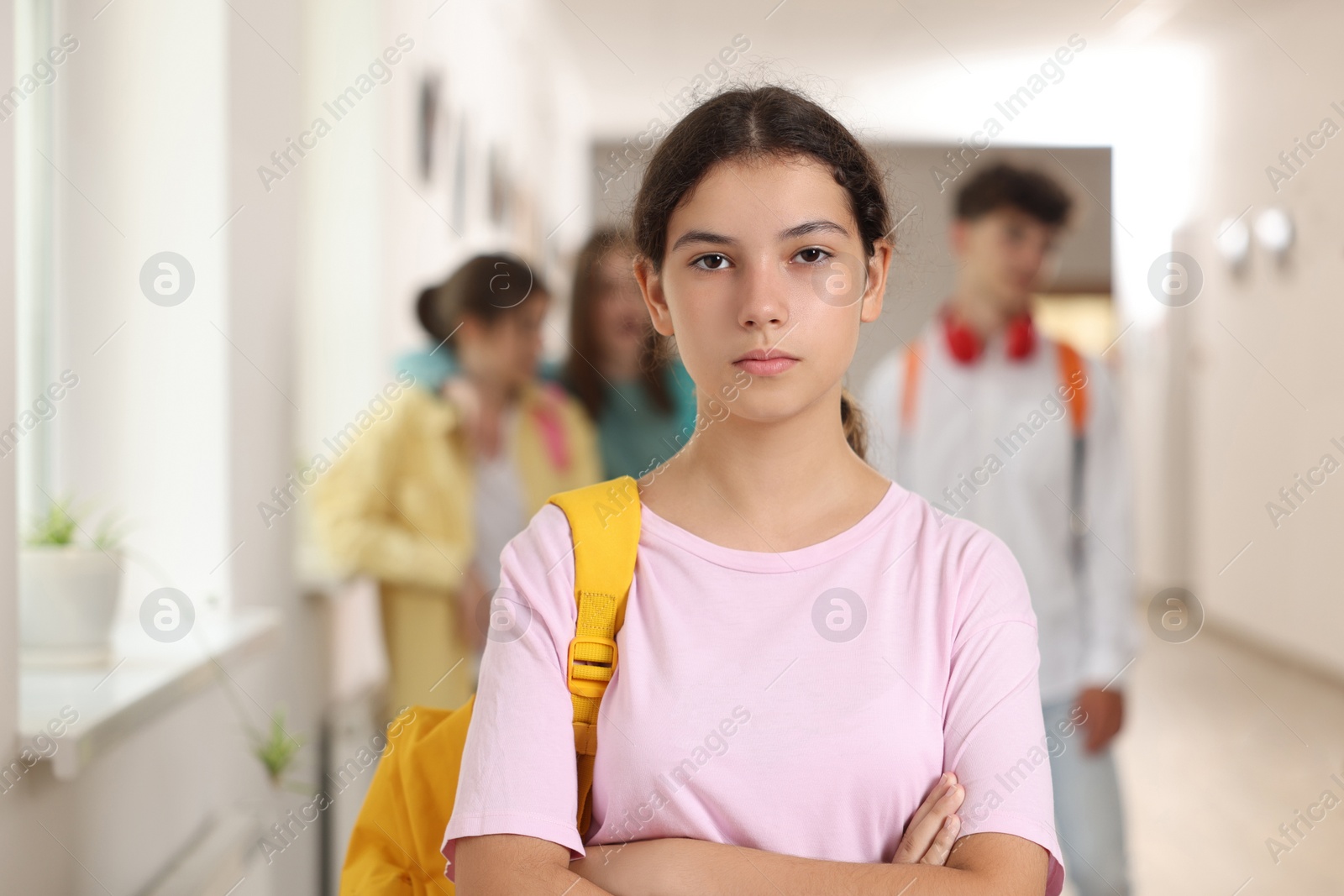 Photo of Teen problems. Lonely girl standing separately from other students at school