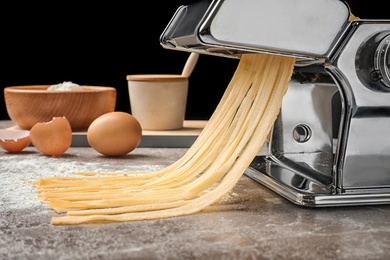 Photo of Pasta maker with dough and products on kitchen table