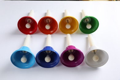 Photo of Set of bright metal hand bells on white background. Montessori musical toy