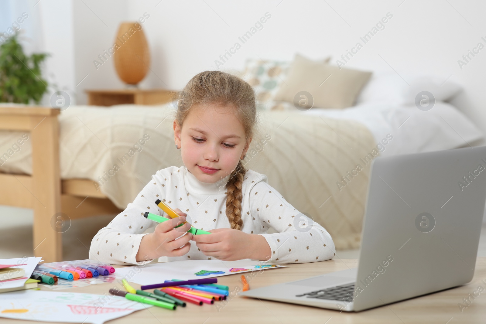 Photo of Little girl drawing with felt-tip pen following online course at home. Time for hobby