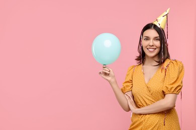 Photo of Happy young woman in party hat with balloon on pink background