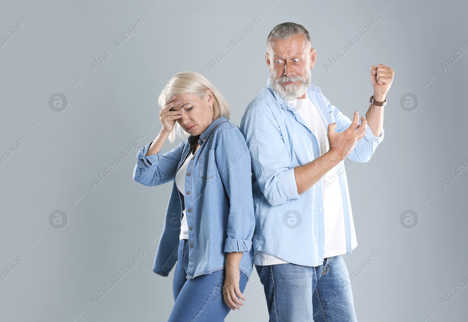 Photo of Mature couple having argument on grey background. Relationship problems